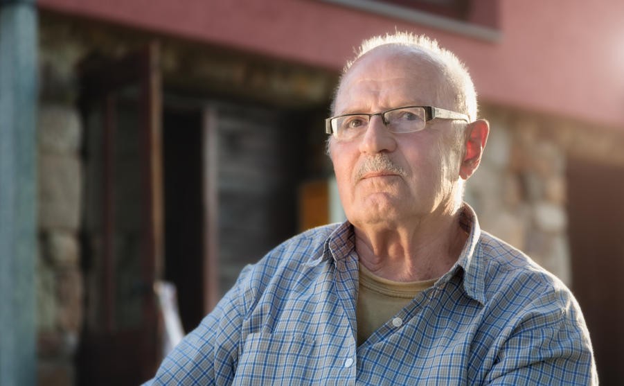 Elderly man sitting in front his house at dawn